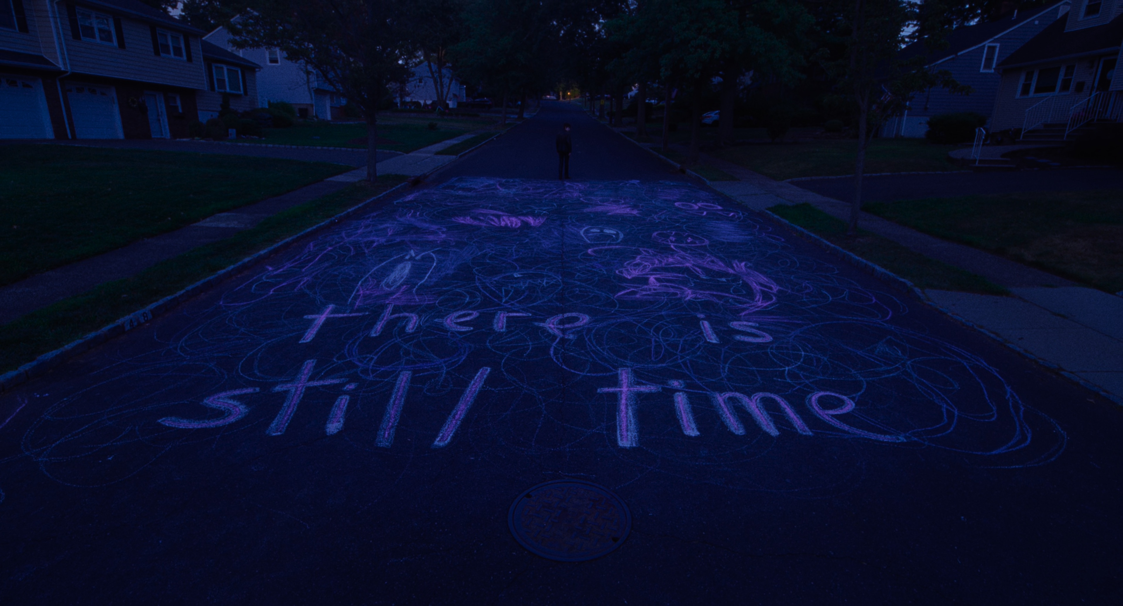 A photo of a street with sidewalk chalk that says 'There is still time'